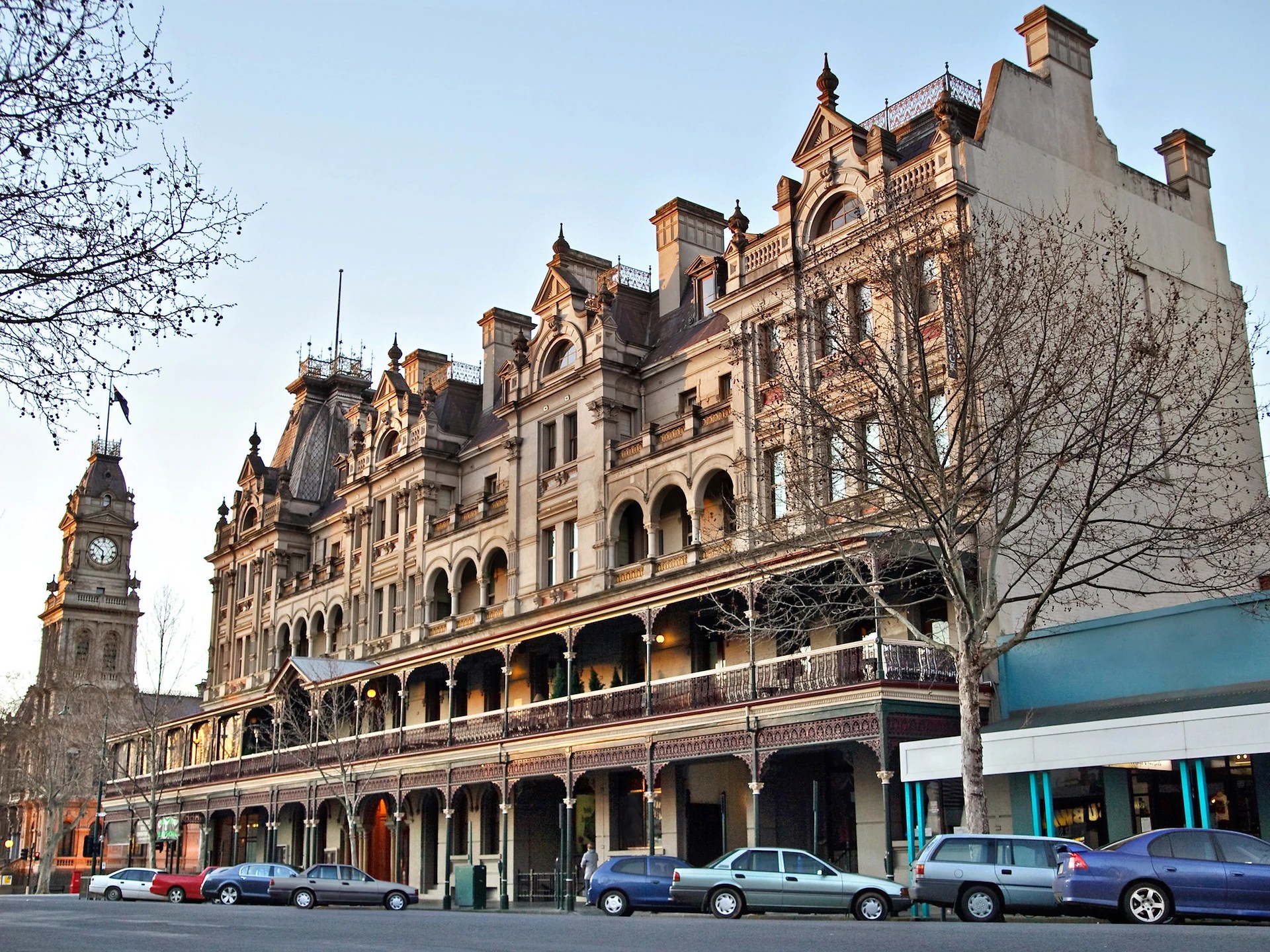 Historic building with ornate architecture and balconies, featuring a clock tower nearby.